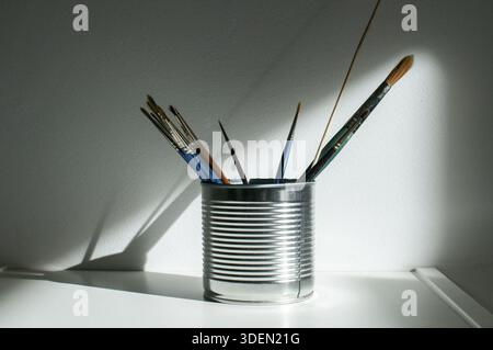 Tin can with paint brushes closeup on white wall background Stock Photo
