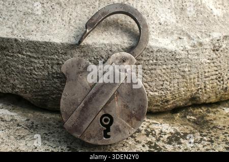 Old weathered grunge retro open padlock closeup on solid stone surface background Stock Photo