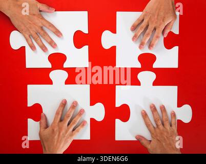 Hands collaborating to complete puzzle solving business problem Stock Photo