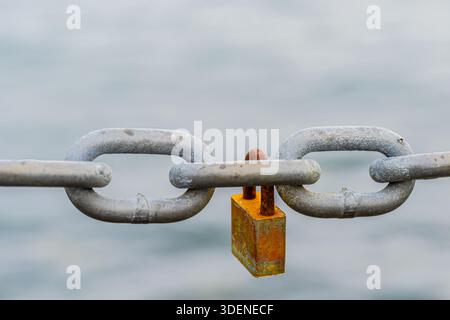 Rusted padlock hanging on a chain Stock Photo