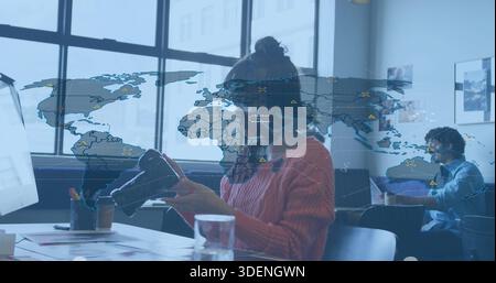 Holding and inspecting VR headset, Asian woman wearing rust sweater and glasses at coworking table Stock Photo