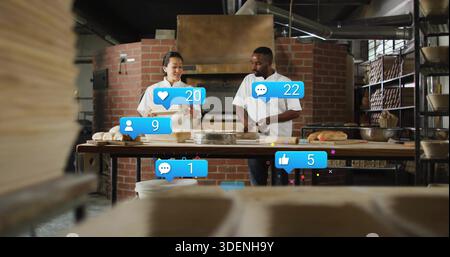 Shaping dough, two bakers in aprons handling loaves at bakery worktable with social media overlays Stock Photo