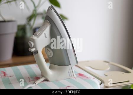 Modern steam iron on ironing board Stock Photo