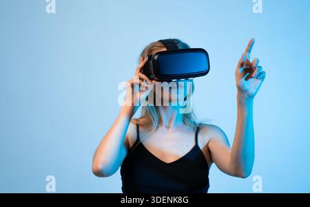 Woman using virtual reality headset and pointing at digital interface, VR design process and interactive user experience Stock Photo