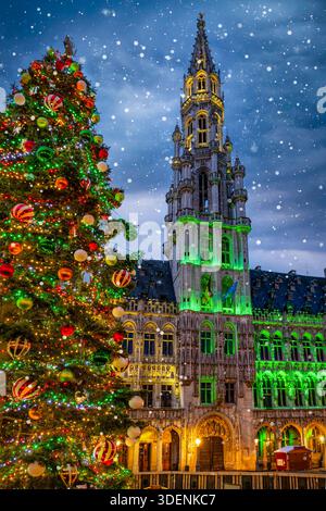 Christmas in Brussels, Belgium, concept with a illuminated, decorated tree in front of the City Hall at the Grand Place square with snow falling Stock Photo