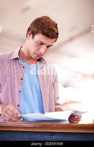 Documents, reading and businessman in office with research for creative project for publishing. Paperwork, report and professional male magazine Stock Photo