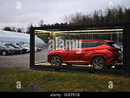 A red SUV is showcased inside a glass, container-like display outdoors, lit from within to emphasize its sleek lines and glossy finish, creating a str Stock Photo