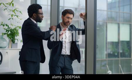 Two multiracial diversity business men in office Caucasian sad frustrated businessman male near window African American guy partner supporting calming Stock Photo