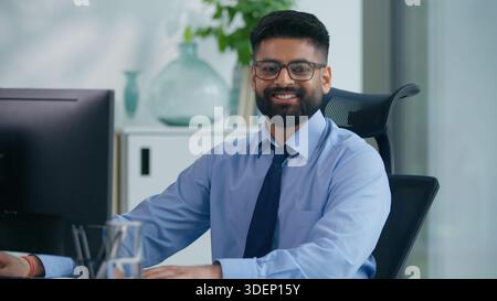 Muslim man Arabian business male worker Indian productive businessman guy working with computer looking at camera smiling happy positive manager Stock Photo