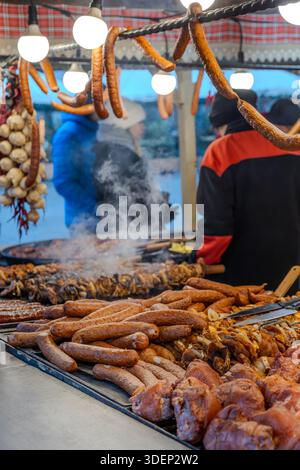Street food stall with sausages and grilled meat cooking over an open grill at a European market. Authentic food culture, local cuisine and culinary t Stock Photo