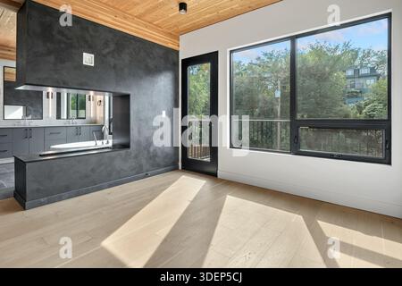 Large open living room with a fireplace and a kitchen. The room is very clean and bright, with a lot of natural light coming in through the windows. T Stock Photo