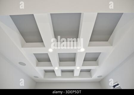 The ceiling is white and has a grid pattern. The lights are on and the room is well lit Stock Photo