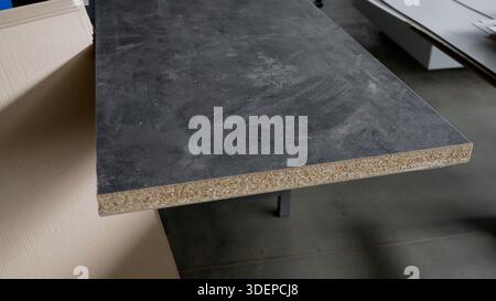 Chipboard panel featuring a dark gray laminate surface, showing the exposed particleboard core for construction and furniture projects Stock Photo