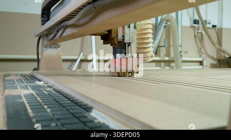 Cnc woodworking machine cutting and shaping a light brown wood panel, manufacturing furniture parts with precision Stock Photo