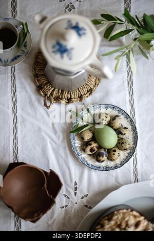 Italian Easter table setting. Natural dyed eggs in green color and quail eggs. Vintage tablecloth. Stock Photo