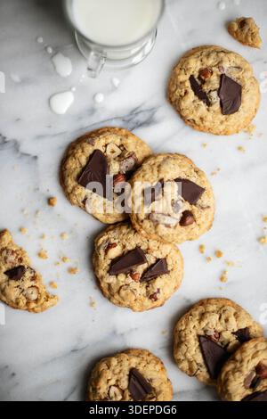 Homemade oat cookies with dark chocolate and hazelnuts on the marble surface. Glass of milk. Top view, flat lay. Stock Photo