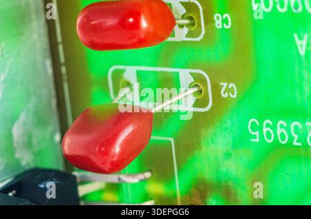 Close-up macro shot of red ceramic capacitors on a green circuit board with visible markings Stock Photo