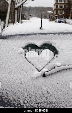 Snow covered car on the street with a love heart drawn on the window Stock Photo