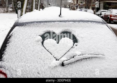 Snow covered car on the street with a love heart drawn on the window Stock Photo