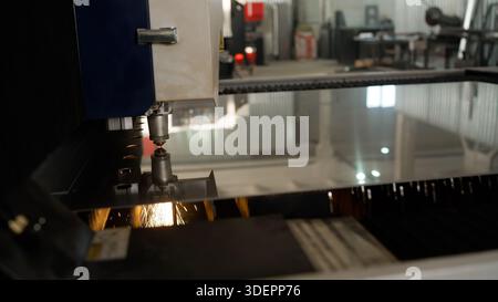 Laser cutting machine performing precise metal fabrication in a factory, creating bright sparks during industrial production Stock Photo