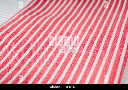 Damaged natural cotton kitchen towel with a hole in it on a wooden table. Stock Photo