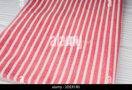 Damaged natural cotton kitchen towel with a hole in it on a wooden table. Stock Photo