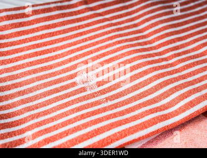 Damaged natural cotton kitchen towel with a hole in it on a wooden table. Stock Photo