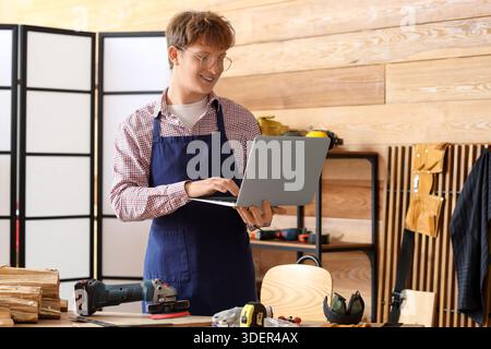 Young carpenter using laptop in workshop Stock Photo