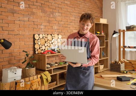 Young carpenter using laptop in workshop Stock Photo