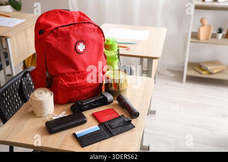 Emergency backpack with necessities on desk in classroom Stock Photo