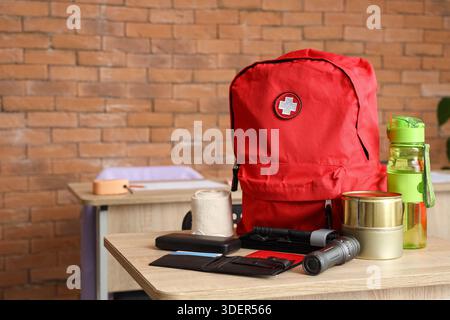 Emergency backpack with necessities on desk in classroom Stock Photo