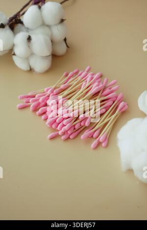Pink cotton swabs arranged on a plain surface with cotton Stock Photo