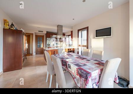 an image of an open kitchen with wooden cabinets and dining room table in mediterranean holiday home Stock Photo