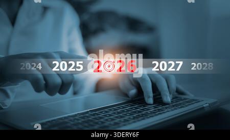 Businessman hands touching virtual 2026 year button with target icon on laptop. Future business planning, success strategy and new year goals for prof Stock Photo