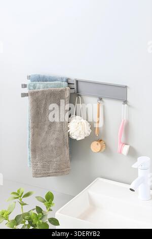 Grey Multi-Arm Swivel Towel Rack with Hanging Brushes on White Bathroom Wall Mockup Stock Photo