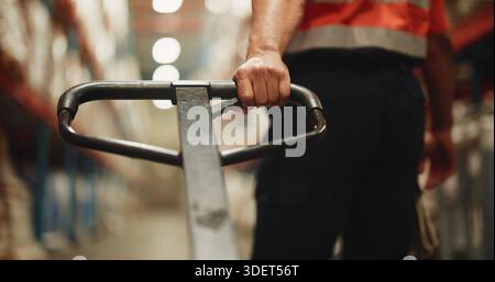 Handle, trolley and hand of worker in warehouse for distribution, cargo or quality assurance. Logistics, freight and male supply chain manager with Stock Photo