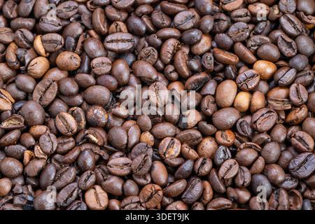 Close-up roasted coffee beans texture showing glossy medium-dark roast, warm brown tones and subtle oil sheen creating cozy breakfast mood for packagi Stock Photo