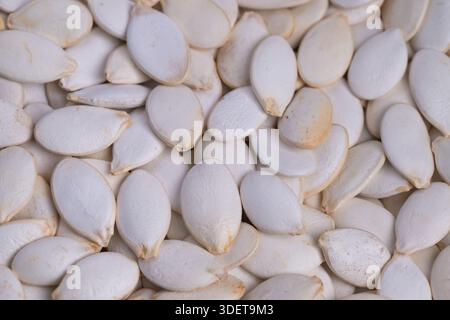 Closeup white pumpkin seeds layered densely showing fine shell texture, soft shadows and neutral tones for backgrounds, packaging and design. Stock Photo
