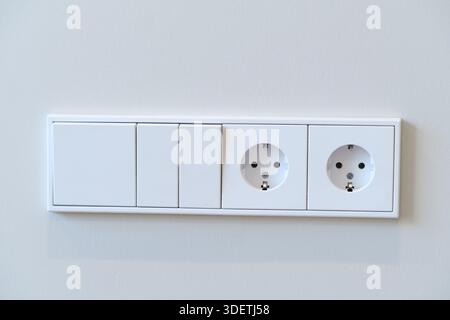 Two Electrical Outlets and Switches on a Plain Wall in a Simple Interior Space Stock Photo