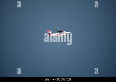 Seaplane of Trans Maldivian Airways airline flying in blue sky. Maldives, Asia Stock Photo
