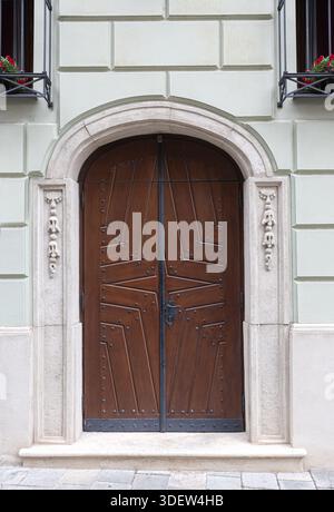 Elaborate geometric pattern on vintage wooden doors with a carved stone archway and facade Stock Photo