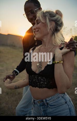 young couple dancing outside at sunset Stock Photo