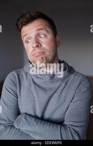 Uncertain male person looking up with hesitation, thinking or feeling skeptical. Stock Photo
