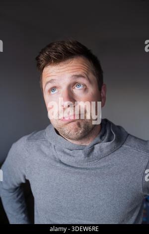 Uncertain male person looking up with hesitation, thinking or feeling skeptical. Stock Photo