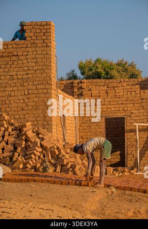 Builders constructing a house from locally-made red bricks. House building alongside the RN7 highway from Fianarantsoa to Ambalavao,  Madagascar Stock Photo