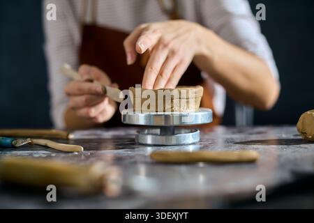Hands mold soft clay into unique pottery, showcasing creativity in an artistic space. Stock Photo