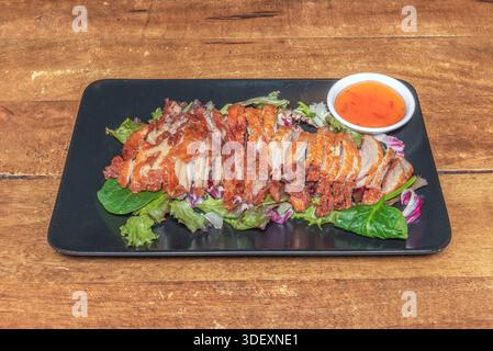 Orange duck, Chinese style, with its signature bright sweet and sour sauce, presented in thin slices on a bed of crispy skin and fresh orange segments Stock Photo