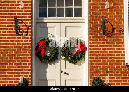 Two Christmas wreaths with pine cones on a white double exterior doors. Stock Photo