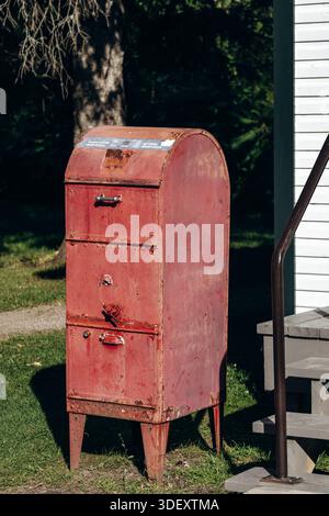 Chambord, Canada - August 18, 2025: Vintage rusted red mail collection box near a post office at Val-Jalbert Historical Village Stock Photo