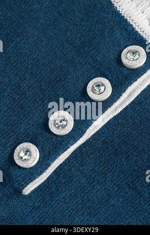 Small crystal buttons on dark blue knit garment closeup as a background Stock Photo